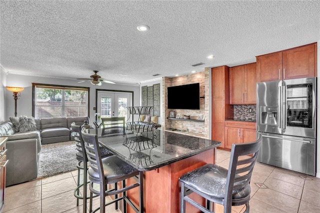 kitchen with stainless steel fridge with ice dispenser, tasteful backsplash, open floor plan, ceiling fan, and a breakfast bar