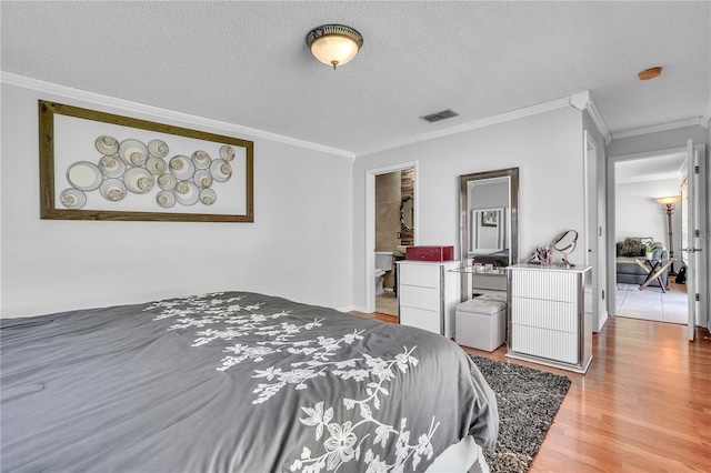 bedroom with crown molding, visible vents, wood finished floors, and a textured ceiling