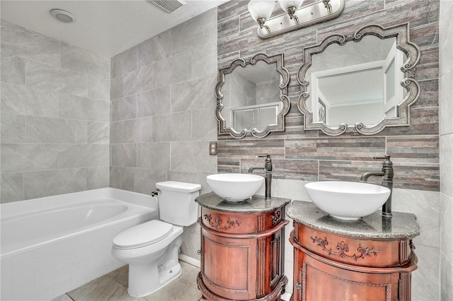 bathroom with vanity, a tub, tile walls, and toilet
