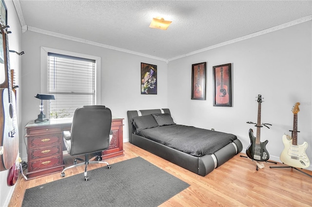 bedroom featuring light wood-style flooring, a textured ceiling, baseboards, and ornamental molding