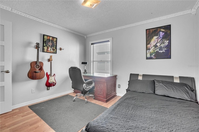 bedroom with baseboards, a textured ceiling, crown molding, and wood finished floors