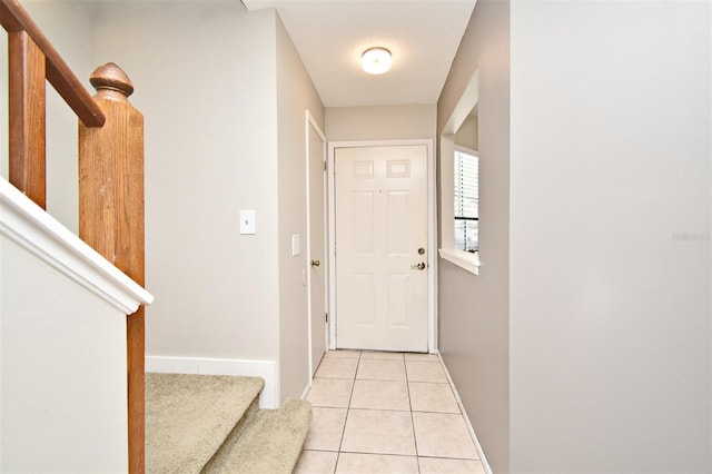 entryway with light tile patterned flooring, baseboards, and stairway