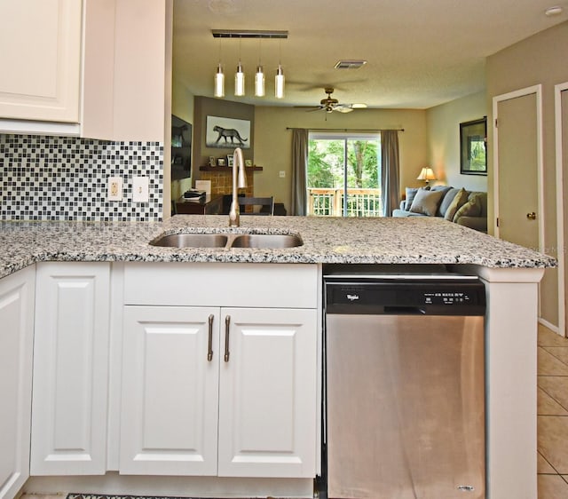kitchen featuring tasteful backsplash, a sink, dishwasher, white cabinets, and light stone countertops