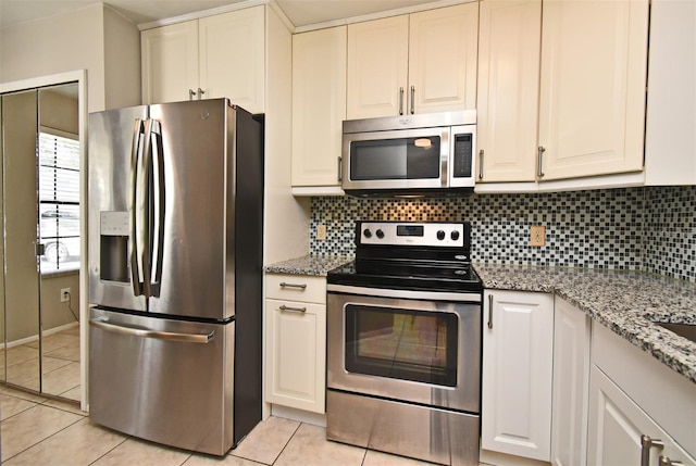 kitchen featuring light tile patterned flooring, white cabinets, stainless steel appliances, light stone counters, and backsplash