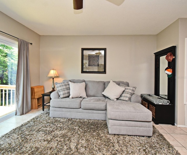 living area with a ceiling fan and light tile patterned floors