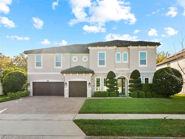 mediterranean / spanish house with an attached garage, driveway, stone siding, and stucco siding