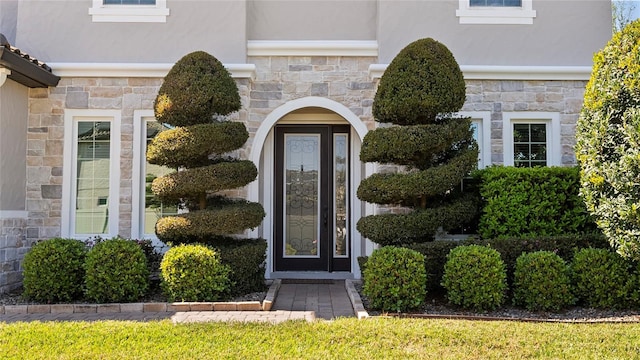 doorway to property featuring stone siding and stucco siding