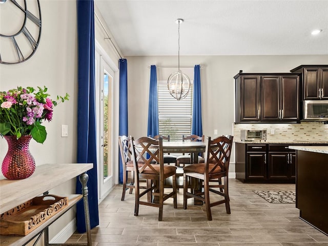 dining room with a toaster, a wealth of natural light, a chandelier, and light wood-type flooring