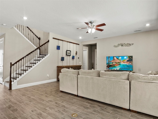 living room with wood finished floors, stairs, and ceiling fan