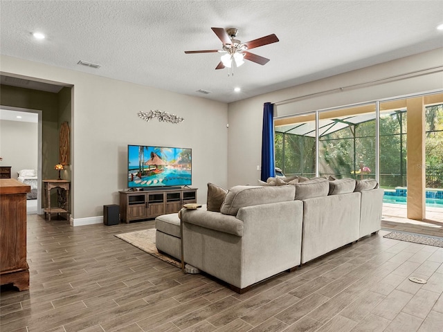 living room featuring wood finished floors, a ceiling fan, visible vents, and a sunroom