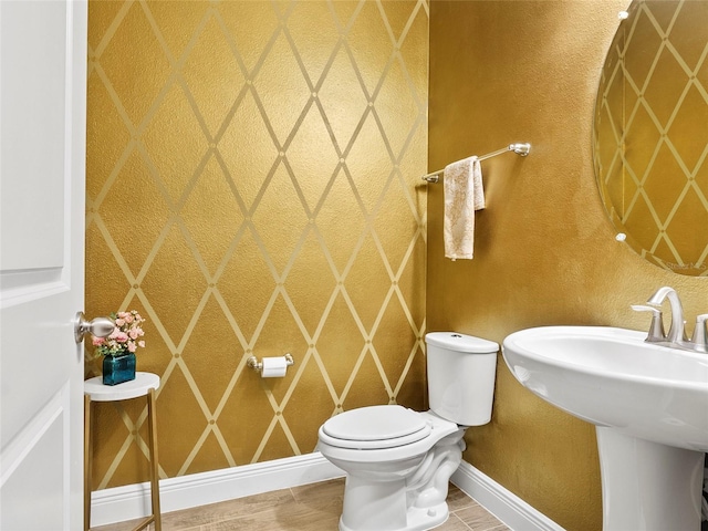bathroom with baseboards, a sink, and toilet