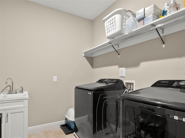washroom featuring baseboards, a sink, washer and dryer, and cabinet space