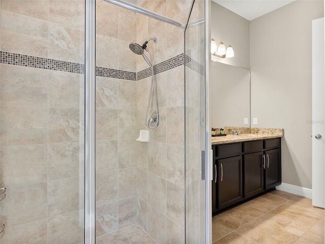 bathroom featuring baseboards, a shower stall, tile patterned floors, and vanity