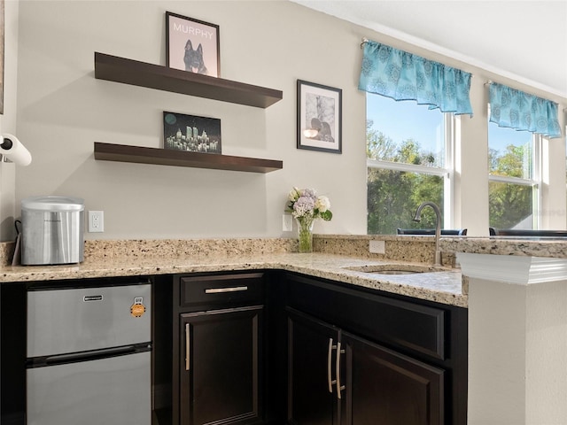 bar with a sink and freestanding refrigerator