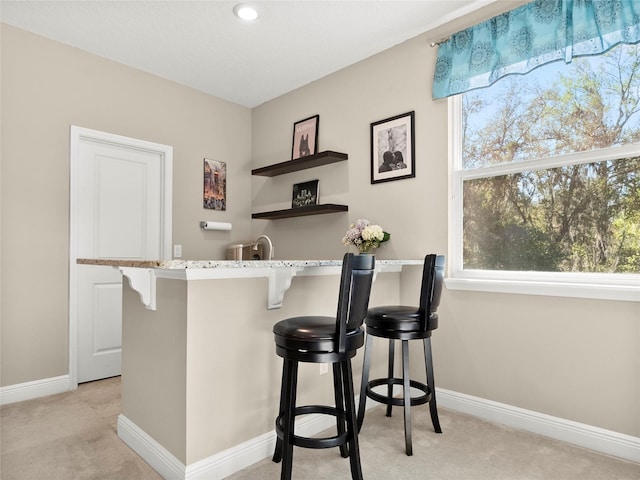 bar featuring recessed lighting, indoor wet bar, light carpet, and baseboards