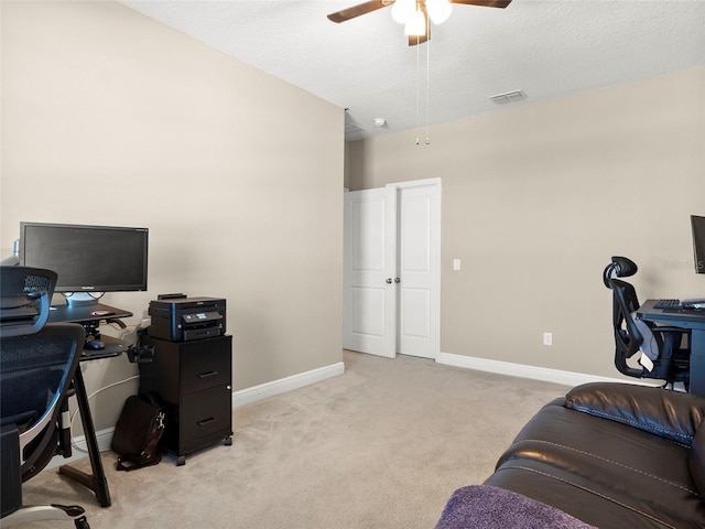 home office featuring a textured ceiling, baseboards, visible vents, light colored carpet, and ceiling fan