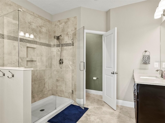 full bathroom with baseboards, vanity, tile patterned flooring, and tiled shower