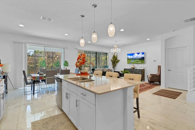 kitchen featuring dishwasher, marble finish floor, a sink, and visible vents