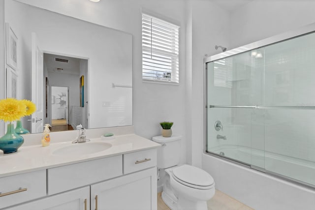 bathroom featuring visible vents, toilet, bath / shower combo with glass door, and vanity
