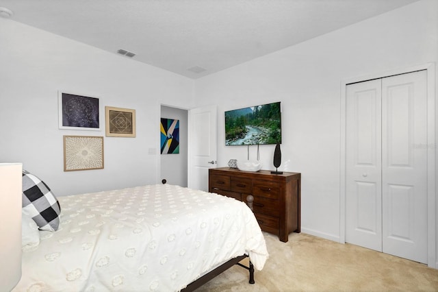 bedroom with a closet, light colored carpet, and visible vents