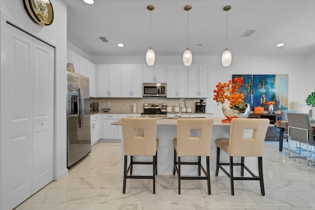 kitchen featuring tasteful backsplash, stainless steel appliances, a breakfast bar, marble finish floor, and visible vents