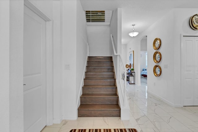 stairs with marble finish floor, baseboards, and arched walkways
