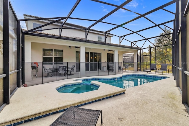 view of swimming pool with a ceiling fan, a pool with connected hot tub, glass enclosure, and a patio