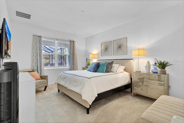 bedroom featuring light colored carpet, visible vents, and a textured ceiling