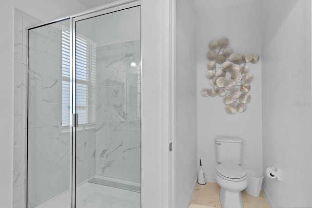 bathroom featuring baseboards, toilet, and a stall shower