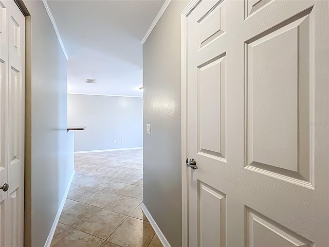 hallway with baseboards, ornamental molding, visible vents, and light tile patterned floors