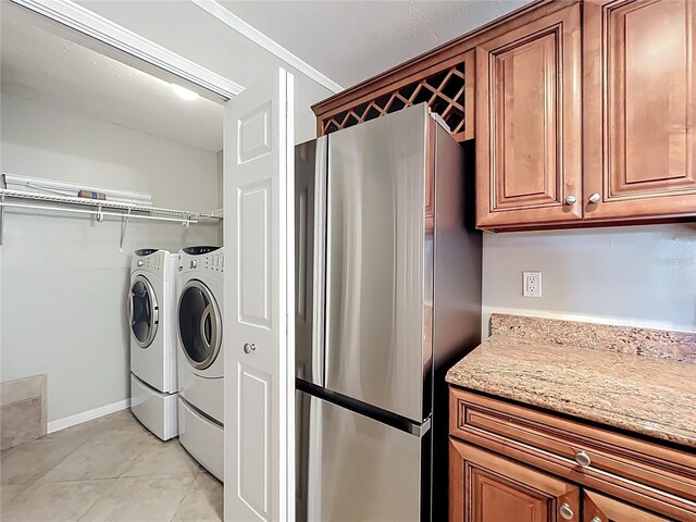 washroom with light tile patterned floors, baseboards, washer and dryer, and laundry area