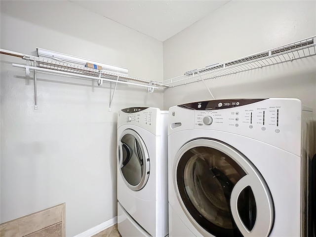 washroom featuring independent washer and dryer, laundry area, and baseboards