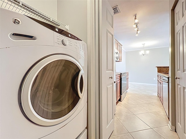 clothes washing area with light tile patterned floors, ornamental molding, washer / dryer, visible vents, and a notable chandelier