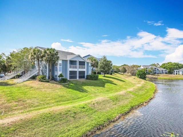 view of side of property featuring a lawn, a water view, and stairway