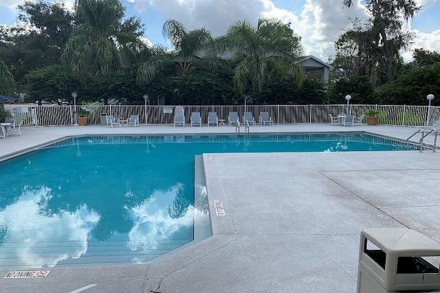 community pool with fence and a patio area