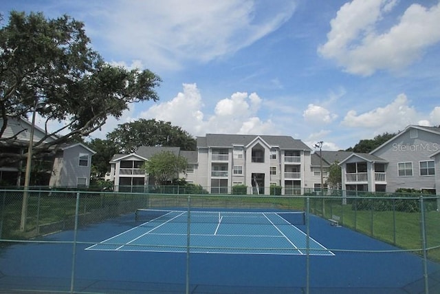 view of tennis court featuring a residential view and fence
