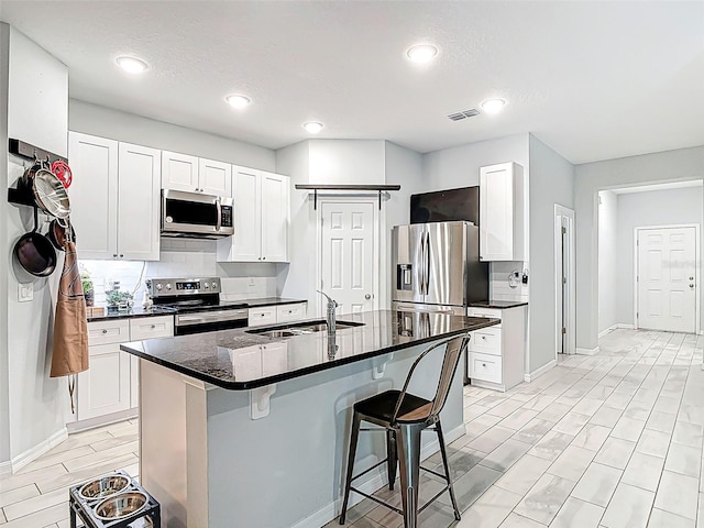 kitchen featuring a sink, stainless steel appliances, a breakfast bar, visible vents, and baseboards