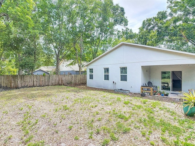 back of property featuring stucco siding and fence