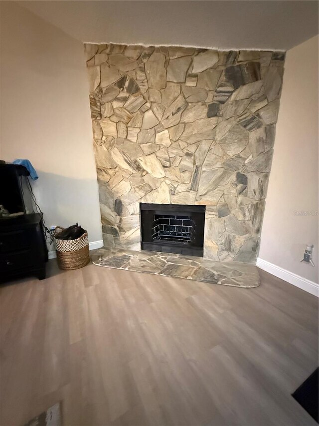 room details with baseboards, heating unit, wood finished floors, and a fireplace