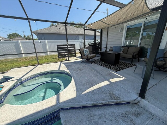 view of pool with a lanai, a patio area, fence, and an in ground hot tub