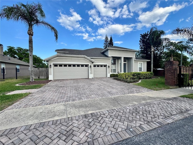 view of front facade featuring a front lawn, fence, a garage, stucco siding, and decorative driveway