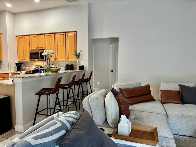living area with recessed lighting, visible vents, a towering ceiling, and baseboards