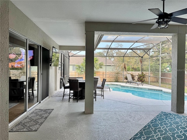 exterior space with glass enclosure, a fenced in pool, a fenced backyard, ceiling fan, and a patio