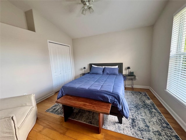 bedroom featuring lofted ceiling, wood finished floors, a ceiling fan, a closet, and baseboards