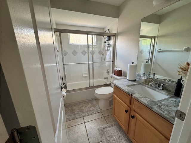 bathroom featuring tile patterned flooring, toilet, vanity, and bath / shower combo with glass door