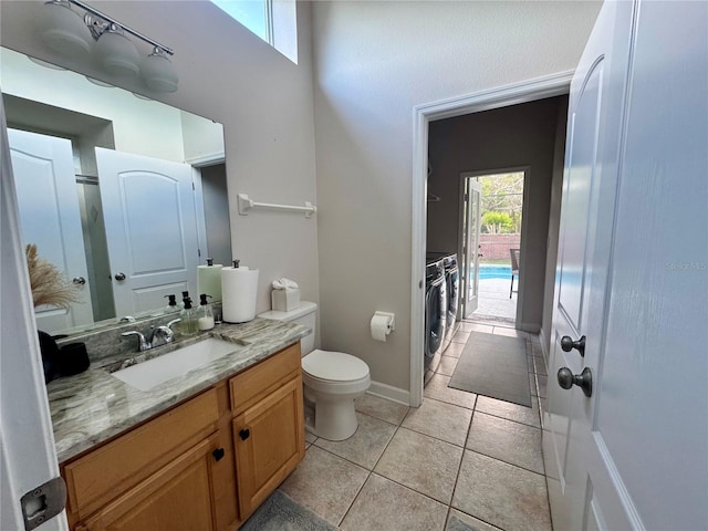 bathroom with tile patterned flooring, toilet, vanity, baseboards, and washer and dryer