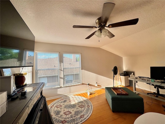 living room with vaulted ceiling, wood finished floors, a textured ceiling, and ceiling fan