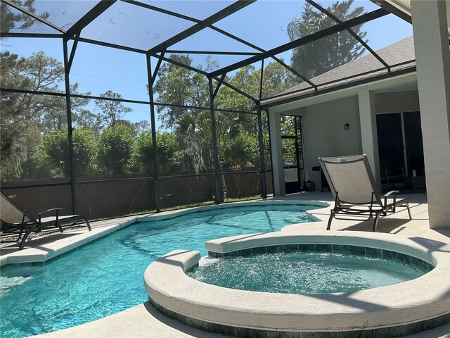 view of pool with glass enclosure, a pool with connected hot tub, and a patio