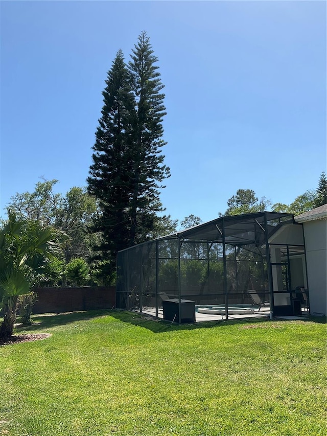 view of yard with fence, an outdoor pool, and a lanai