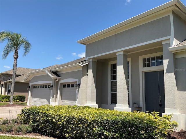 view of front of home with an attached garage, concrete driveway, and stucco siding